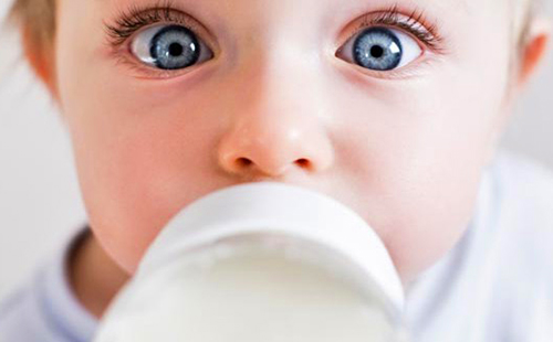 Огромни очи на едно щастливо дете с бутилка мляко