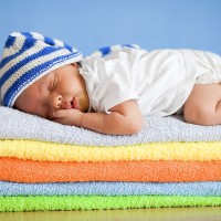 Спящо дете на купчина многоцветни кърпи