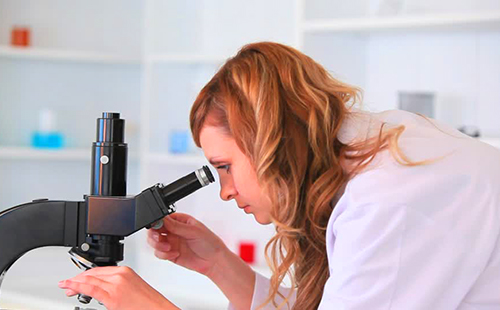Едно момиче изследва мостри в микроскоп