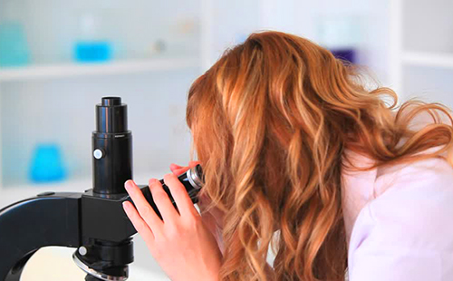 Червенокоси момиче гледа през микроскоп