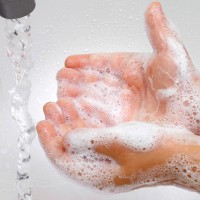 Ръцете на сапунени деца се привличат към течащата вода