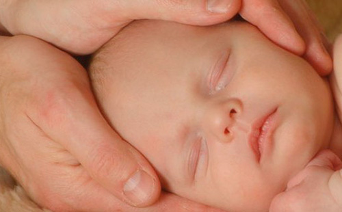 Главата на бебето в дланите