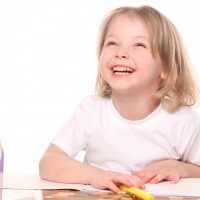 Малкото момиче рисува с моливи и усмивки
