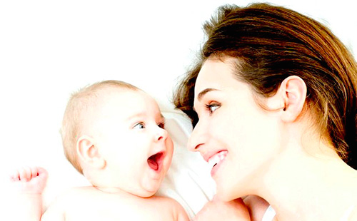 Млада майка гледа към бебето и се смее