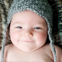 Бебе в плетена шапка се усмихва