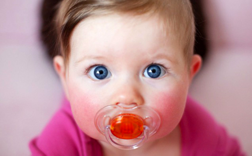 Бебе с огромни сини очи и биберон в устата си