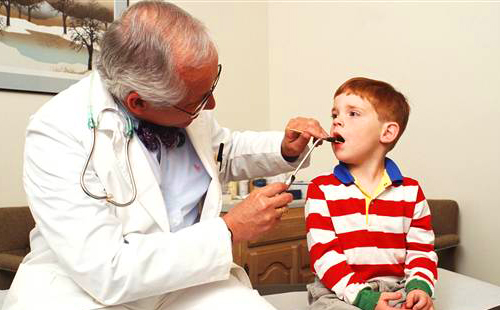 Един стар и опитен лекар разглежда момче с риза с райета