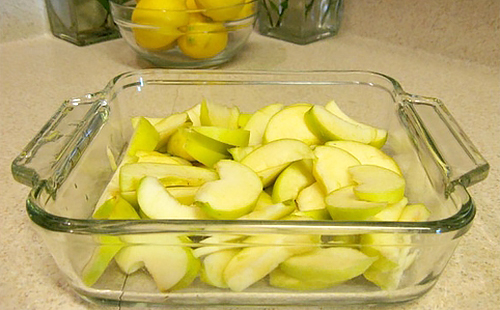 Нарязани зелени ябълки в топлоустойчив стъклен тиган