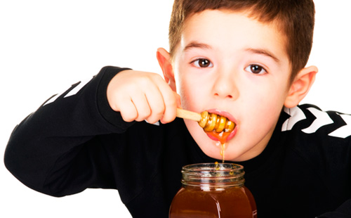 Едно момче яде мед от кутия