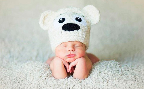 Новородено в плетена бяла шапка