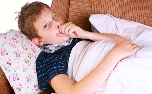 Момчето лежи в леглото с възлово гърло и кашлица