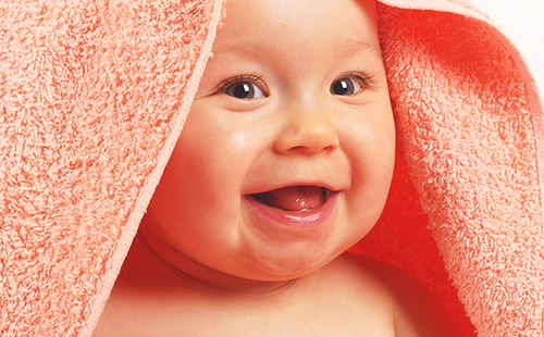 Прясно измито и много доволно бебе в оранжева кърпа