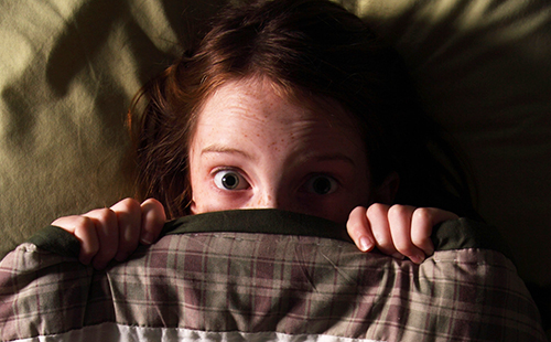 Момичето се страхува от тъмнината и се крие под одеялото