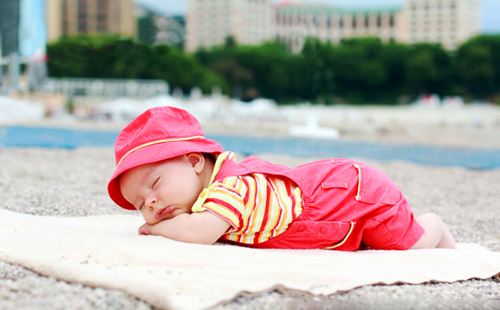 Бебето в розово спи на плажа