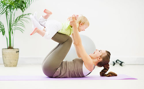 Млада жена, която прави упражнения с бебето