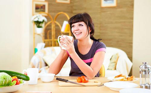 Млада жена седи на маса и пие чай