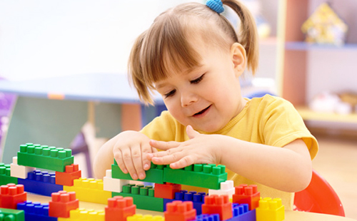 Момиче, което играе с цветни блокове от лего
