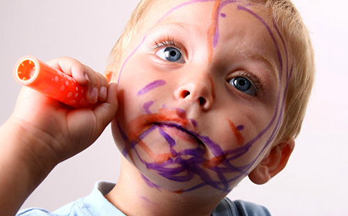 Момчето яростно рисува лицето си с химикалки