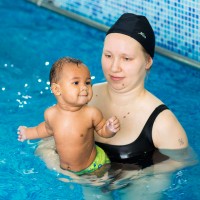Мама в черен бански предпазва внимателно хлапето си