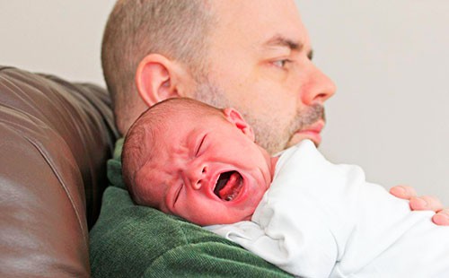 Бебето плаче по рамото на баща си