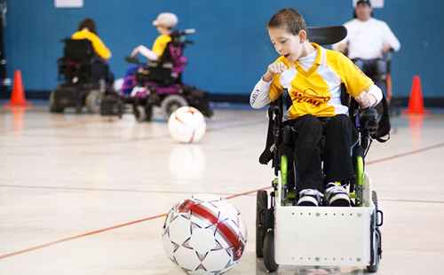 Децата във фитнеса играят футбол за инвалидни колички