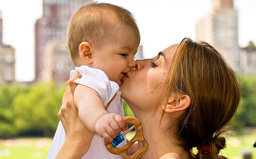 Мама целува бебе на слънчев парк