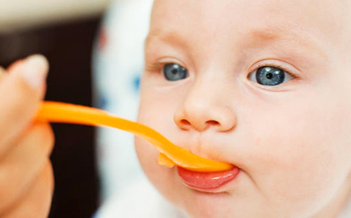 Хлапето се радва на ядене на витамини с оранжево-оранжева лъжица