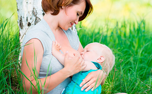 Една жена кърми бебе в природата