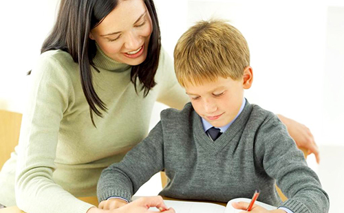 Мама помага на първокласник да си постави домашна работа