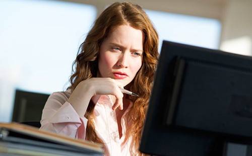Една жена замислено гледа на екрана на компютъра