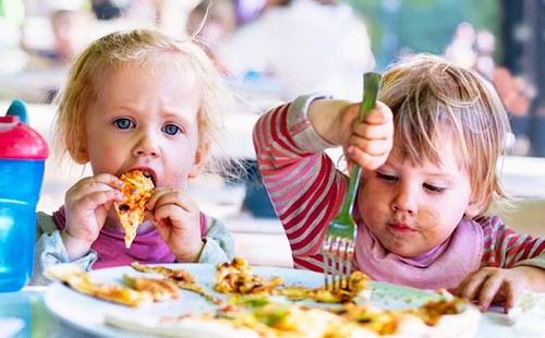 Две деца тъкат пица заедно