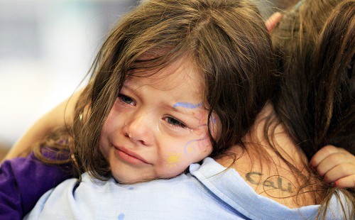 Едно момиче плаче по рамото на майка си след тежък ден