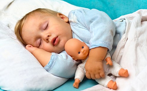 Спящото дете прегръща марионетка