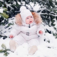 Бебе на бял гащеризон седи на снега
