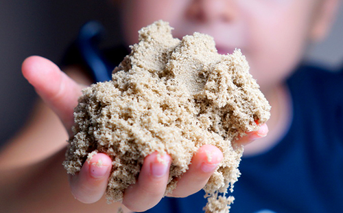 Ръката на детето се простира върху шепа пясък