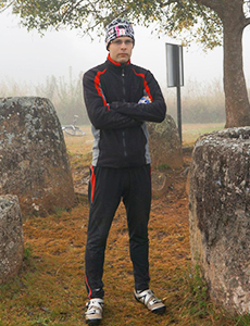 Инструкторът в черен тренировъчен костюм стои сред големите камъни