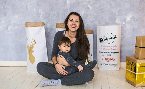 Ирина и бебето седят на пода сред пакетите