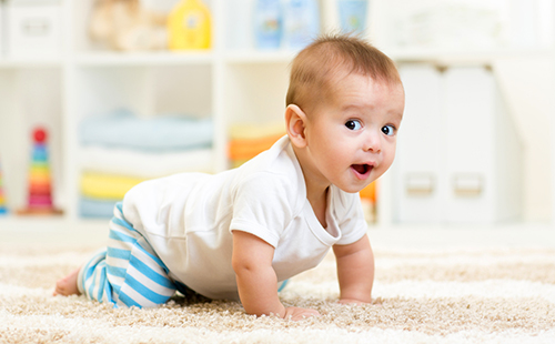 Веселото бебе пълзя по лек килим