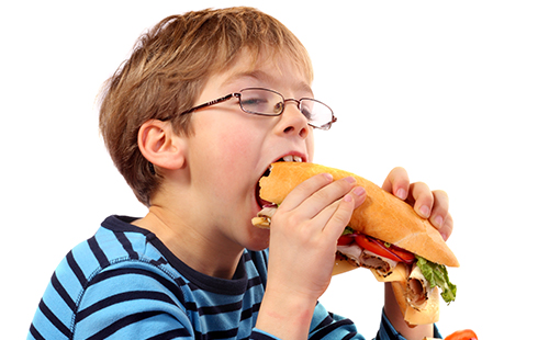 Момчето яде хамбургер