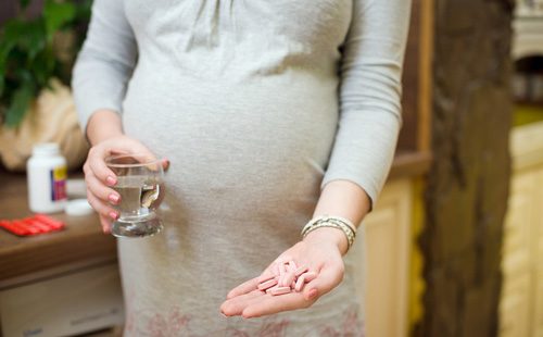 Таблетки в ръцете на бременна жена