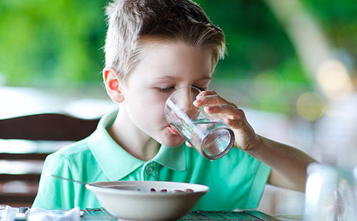 Момче на закуска пие вода от чаша
