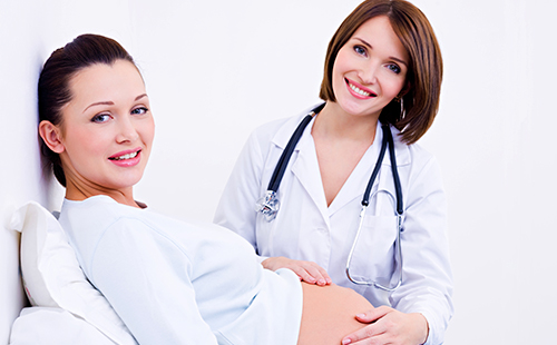Женски лекар леко докосва бременна корема
