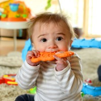 При детето зъбите се отрязват и той дъвче оранжева играчка