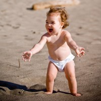 Весело бебе в пелена работи по плажа