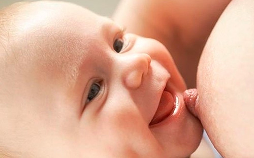Бебето в гърдите се усмихва на майка си