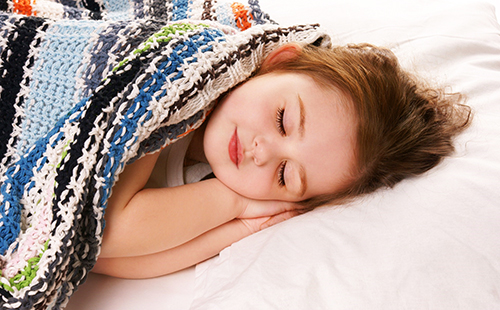 Сладко момиче удобно спи под колоритно одеяло