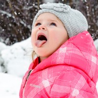 Бебе в розово яке хваща снежинки